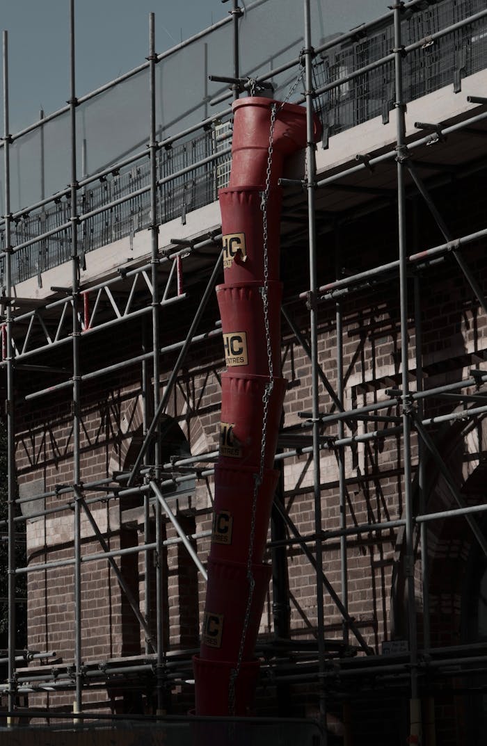 Detailed shot of red chute and scaffolding at a construction site, showcasing industrial safety and equipment.